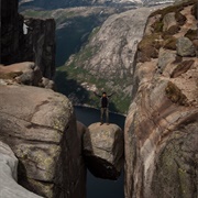 Stand on a Boulder Wedged Between Mountains at Kjeragbolten in Norway
