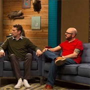 4. David Cross Wears a Red Polo Shirt & Brown Shoes With Red Laces