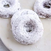 Powdered Sugar Chocolate Ring Donut With Blue Drizzle and Sprinkles
